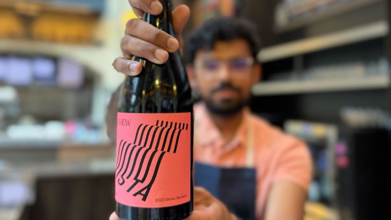 Purav holding a bottle of wine to the camera